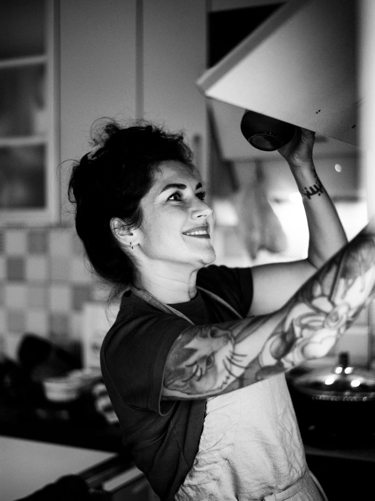 Portrait of the pastry and pizza chef plating a pizza at the wood-fired hearth.