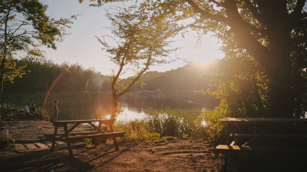 The heated lakeside patio at The Coppermine Pub at golden hour, with string lights and a wood-fired hearth glowing over the water