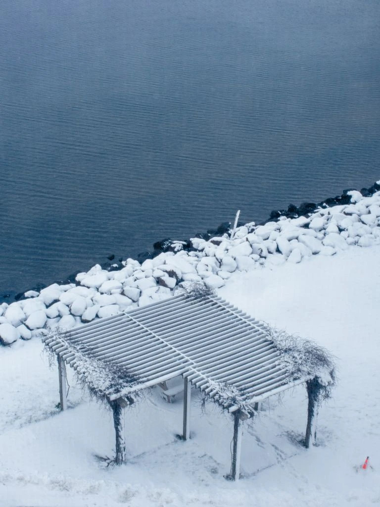 The heated 60-seat lakeside patio at dusk, set with a long harvest table and string lights.
