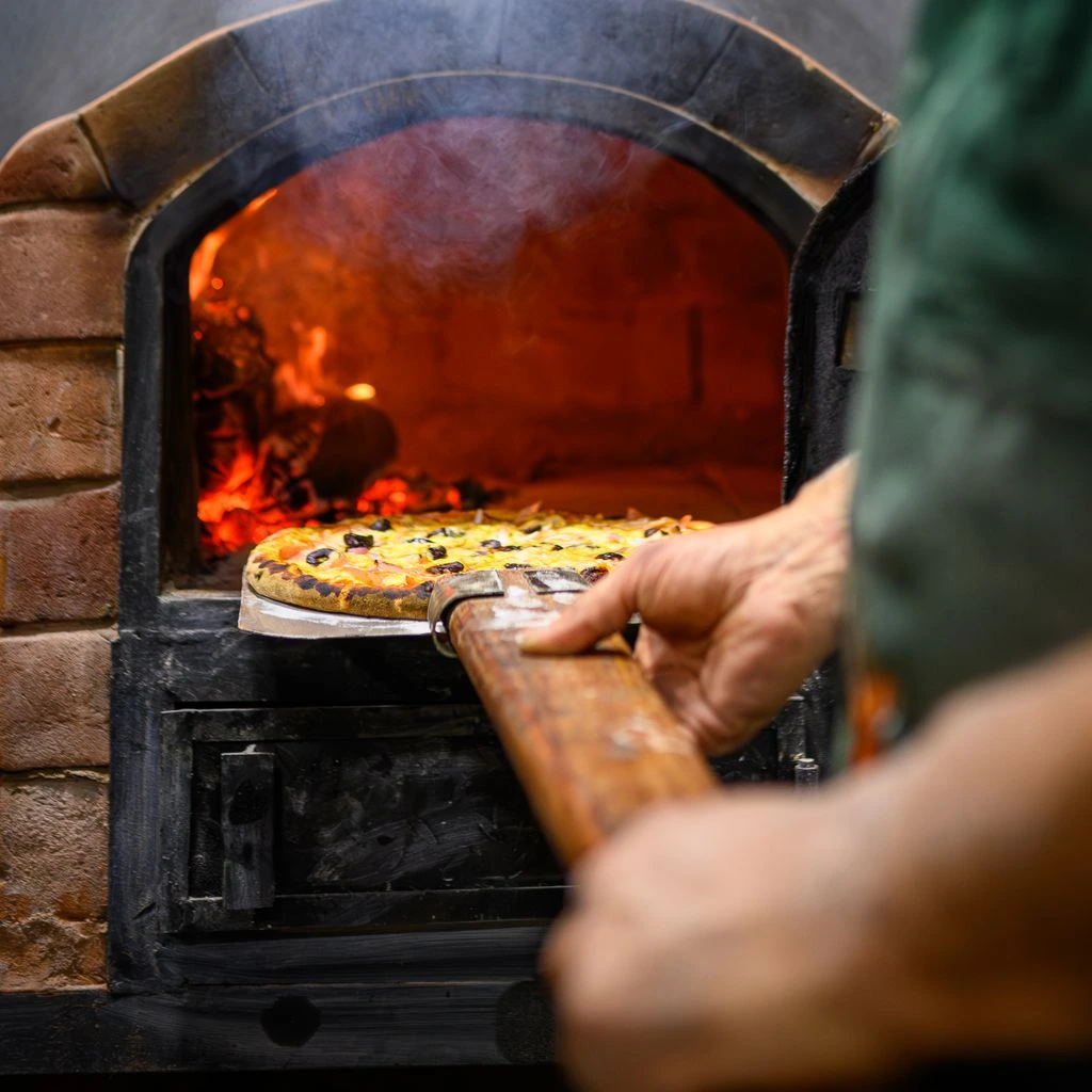 A wood-fired pizza pulled from the 480°C stone hearth, the foundation of our private-event menus.